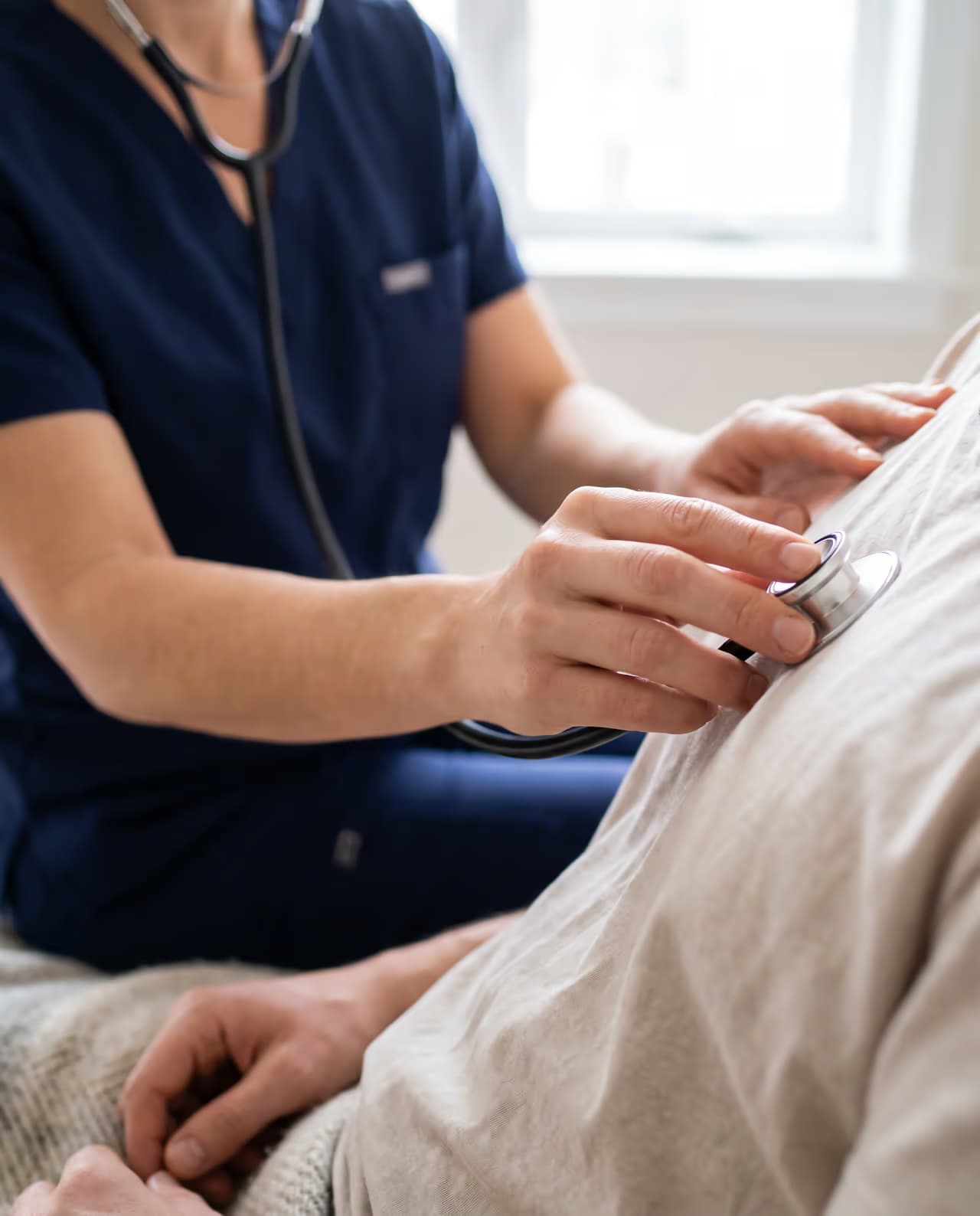 Mani di un medico che visita un paziente con lo stetoscopio